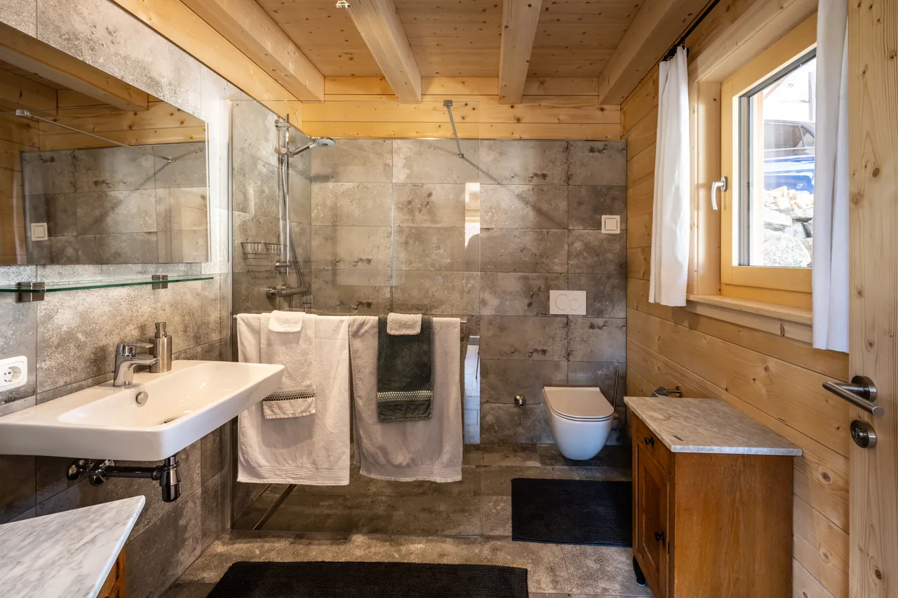 Badezimmer mit bodengleicher Dusche, Waschbecken und Holzdecke