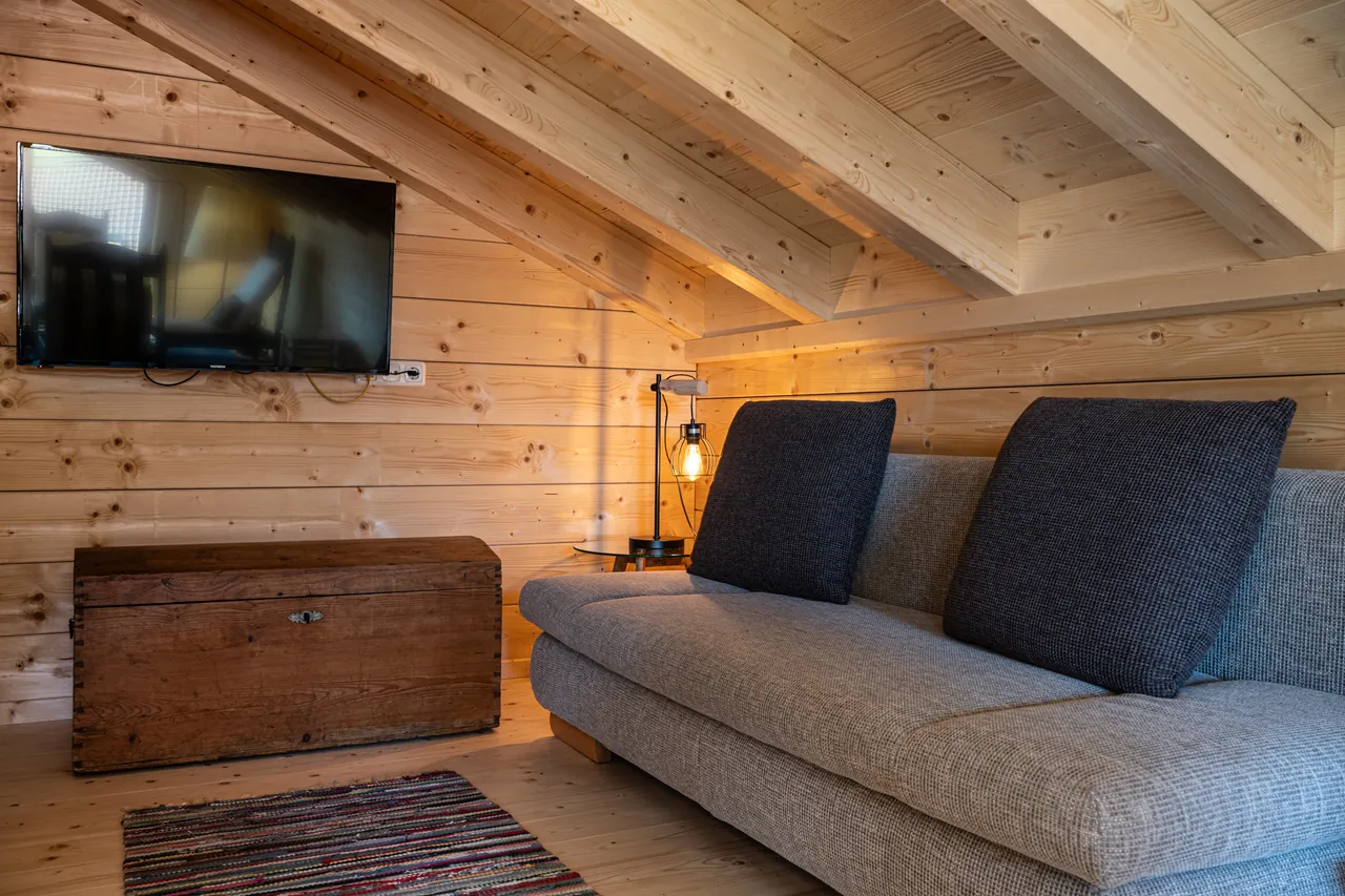 Fernsehecke auf der Galerie mit Sofa und alter Holztruhe unter der Dachschräge
