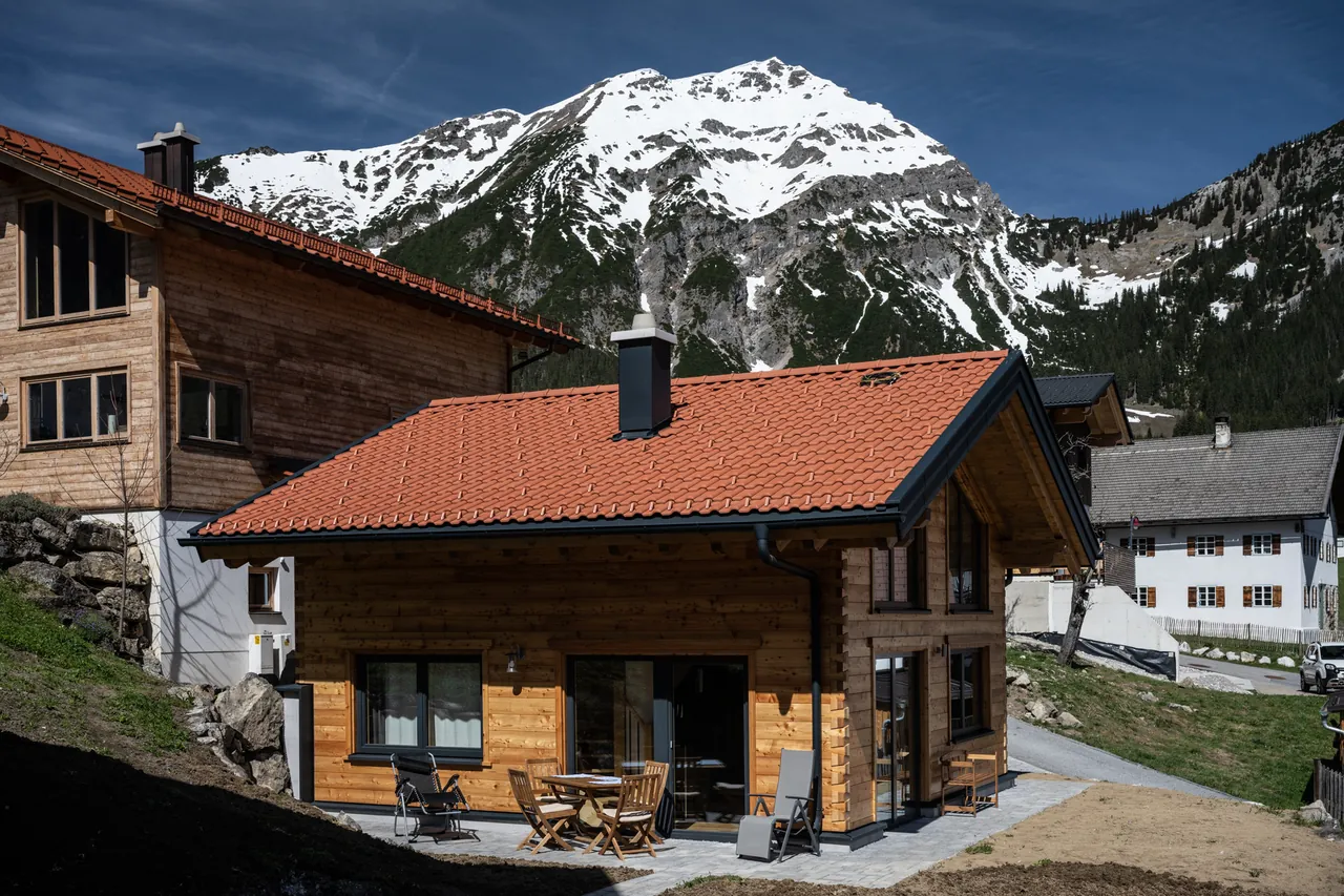 Das Ferienhaus im Frühjahr, dahinter ein noch verschneiter Gipfel