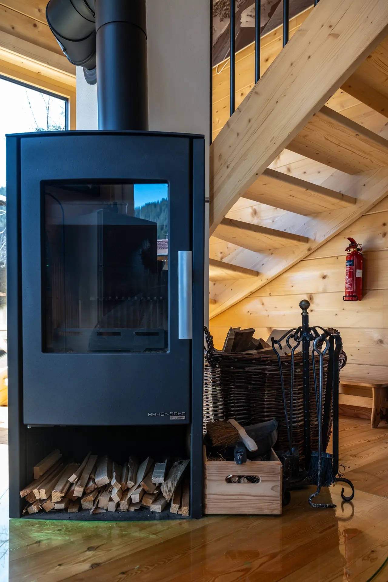 Schwarzer Kaminofen mit Holzvorrat neben der Holztreppe