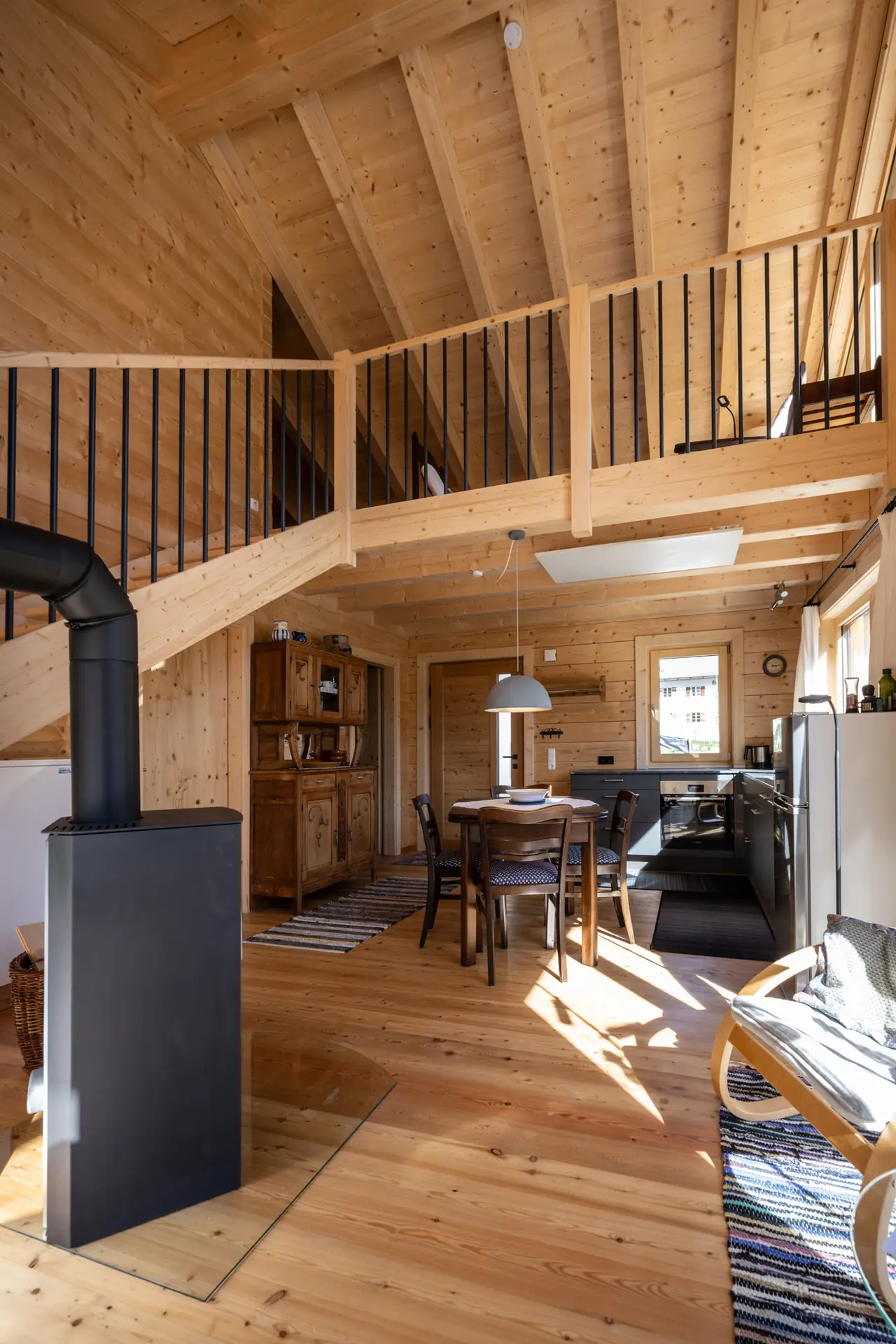 Kaminofen im offenen Wohnraum, darüber die Galerie mit Holzgeländer