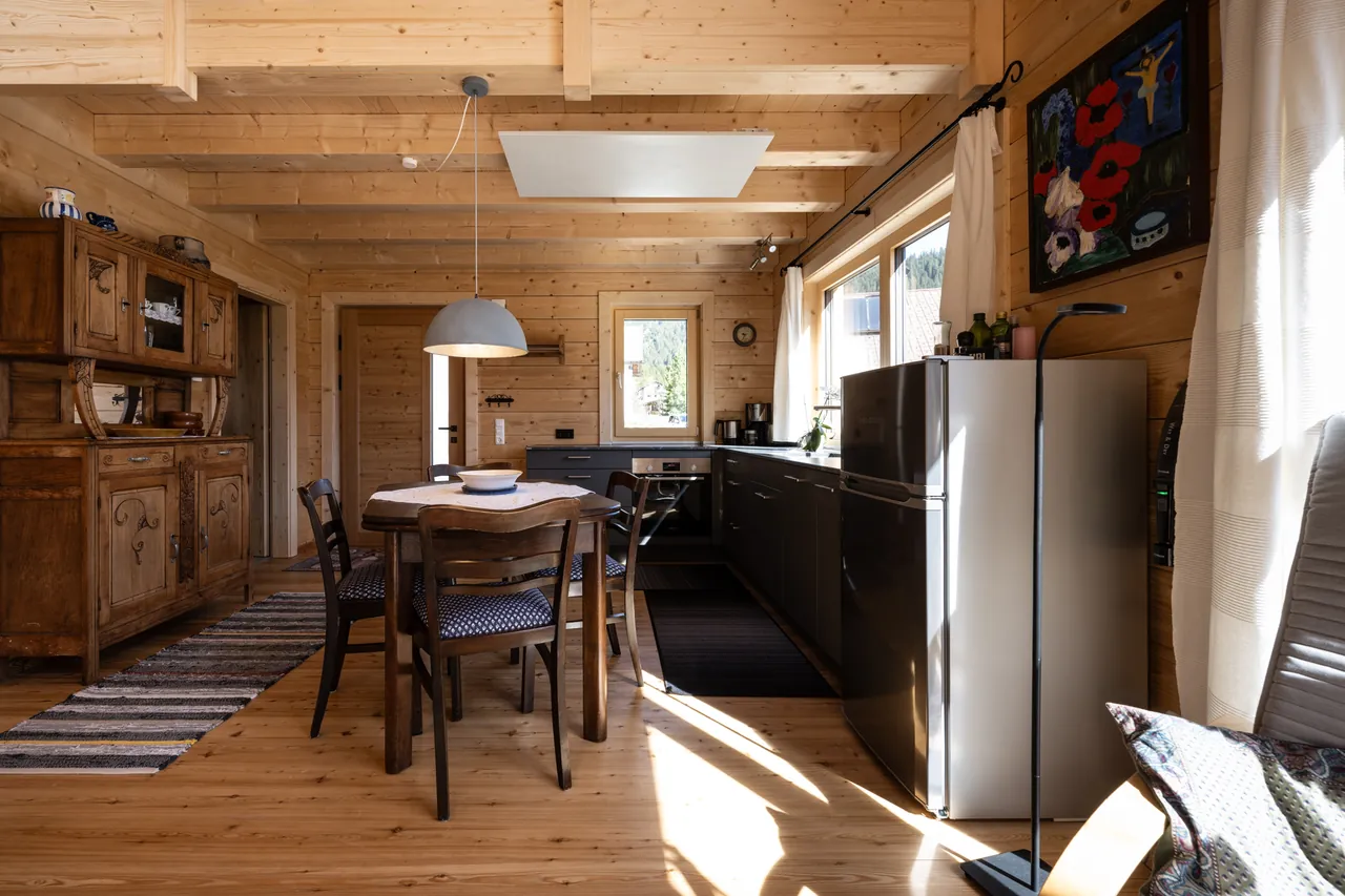 Küchenzeile mit Backofen und Kühlschrank, davor der Esstisch