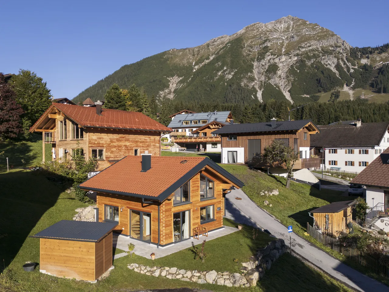 Blick von oben auf das Holzhaus 171 und die umliegenden Häuser von Berwang vor einem Berg