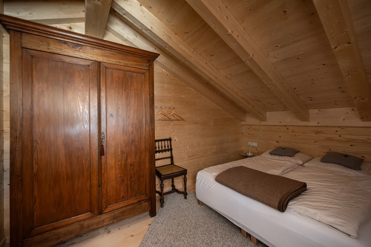 Schlafzimmer im Dachgeschoss mit antikem Kleiderschrank unter der Dachschräge