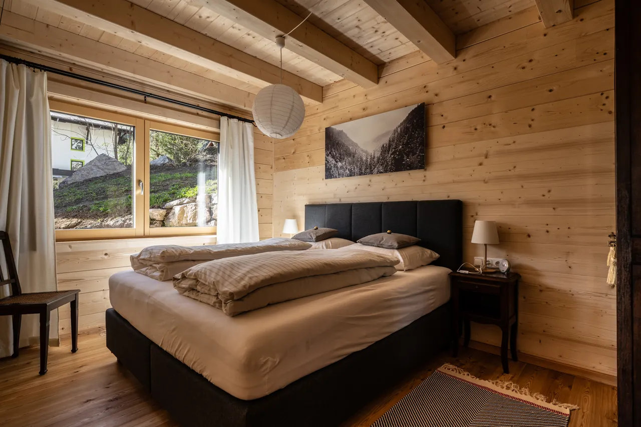 Schlafzimmer im Erdgeschoss mit Doppelbett, Holzwänden und Fenster