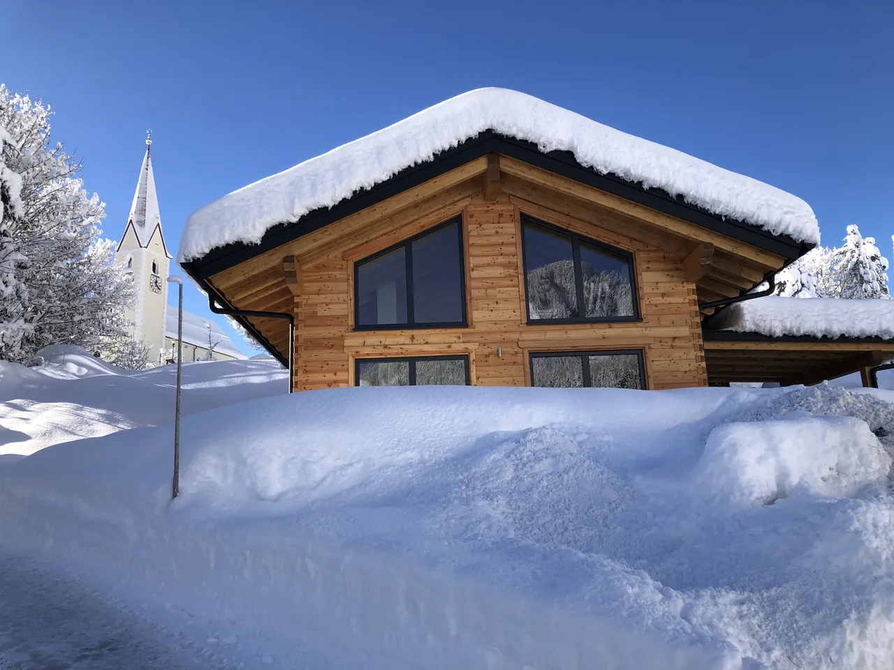 Holzhaus 171 im Schnee mit Blick auf den Kirchturm von Berwang
