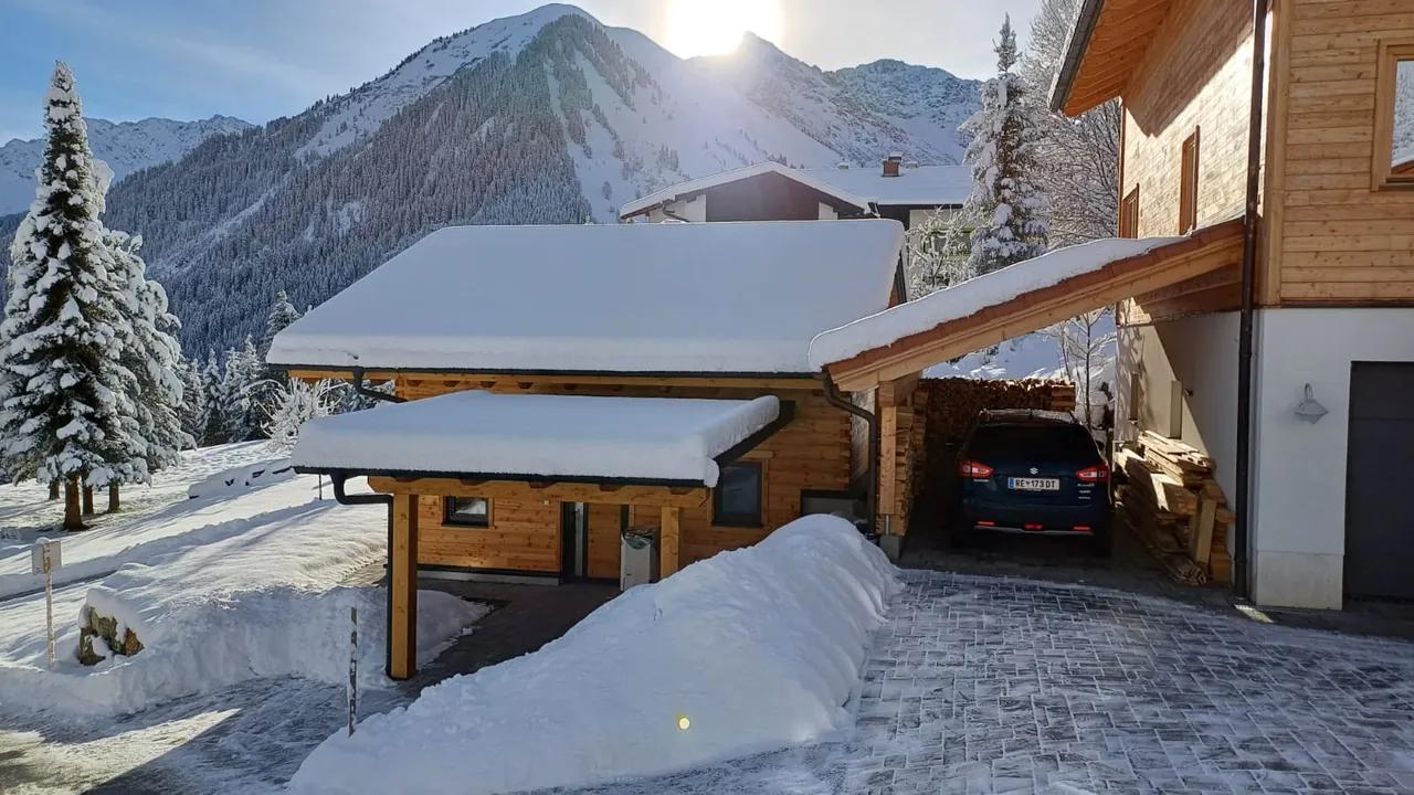 Verschneites Vordach am Holzhaus 171 mit Blick auf die winterlichen Berge über Berwang