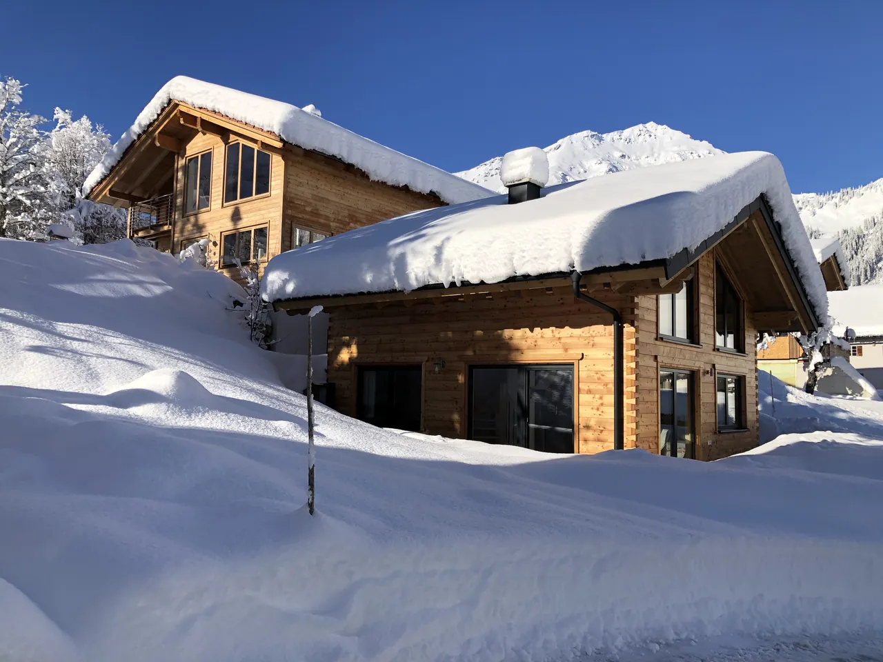 Das Ferienhaus und dahinter das Wohnhaus der Gastgeber in Berwang, beide tief verschneit, im Hintergrund ein verschneiter Gipfel
